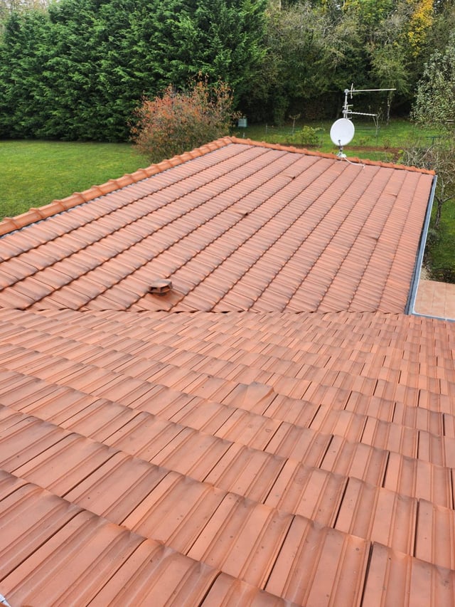 Toiture en tuiles terre cuite propre après nettoyage, vue sur le jardin et la campagne