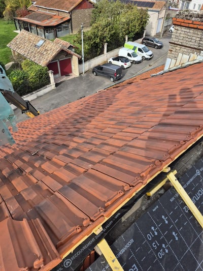 Tuiles en cours de pose sur écran sous-toiture, maisons du village en contrebas