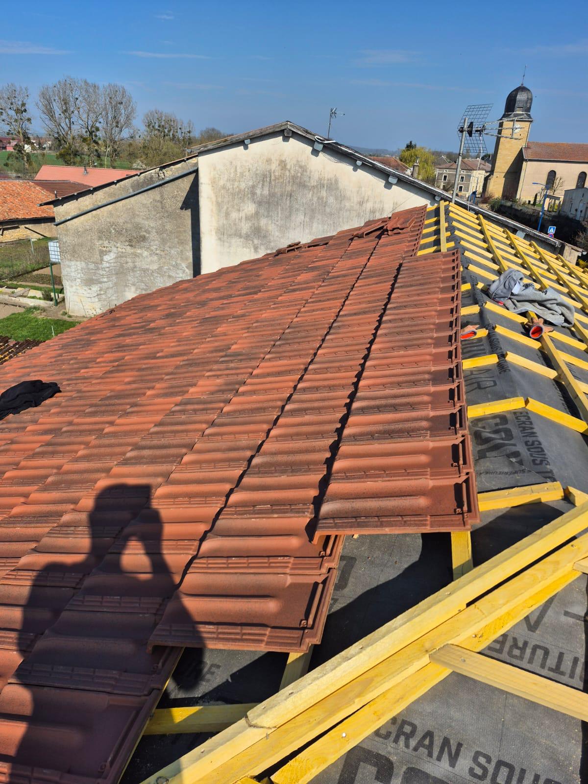 Pose de tuiles neuves sur les liteaux, échafaudage de chantier le long de la toiture