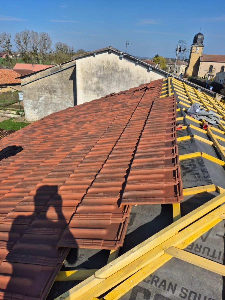 Pose de tuiles neuves sur les liteaux, échafaudage de chantier le long de la toiture